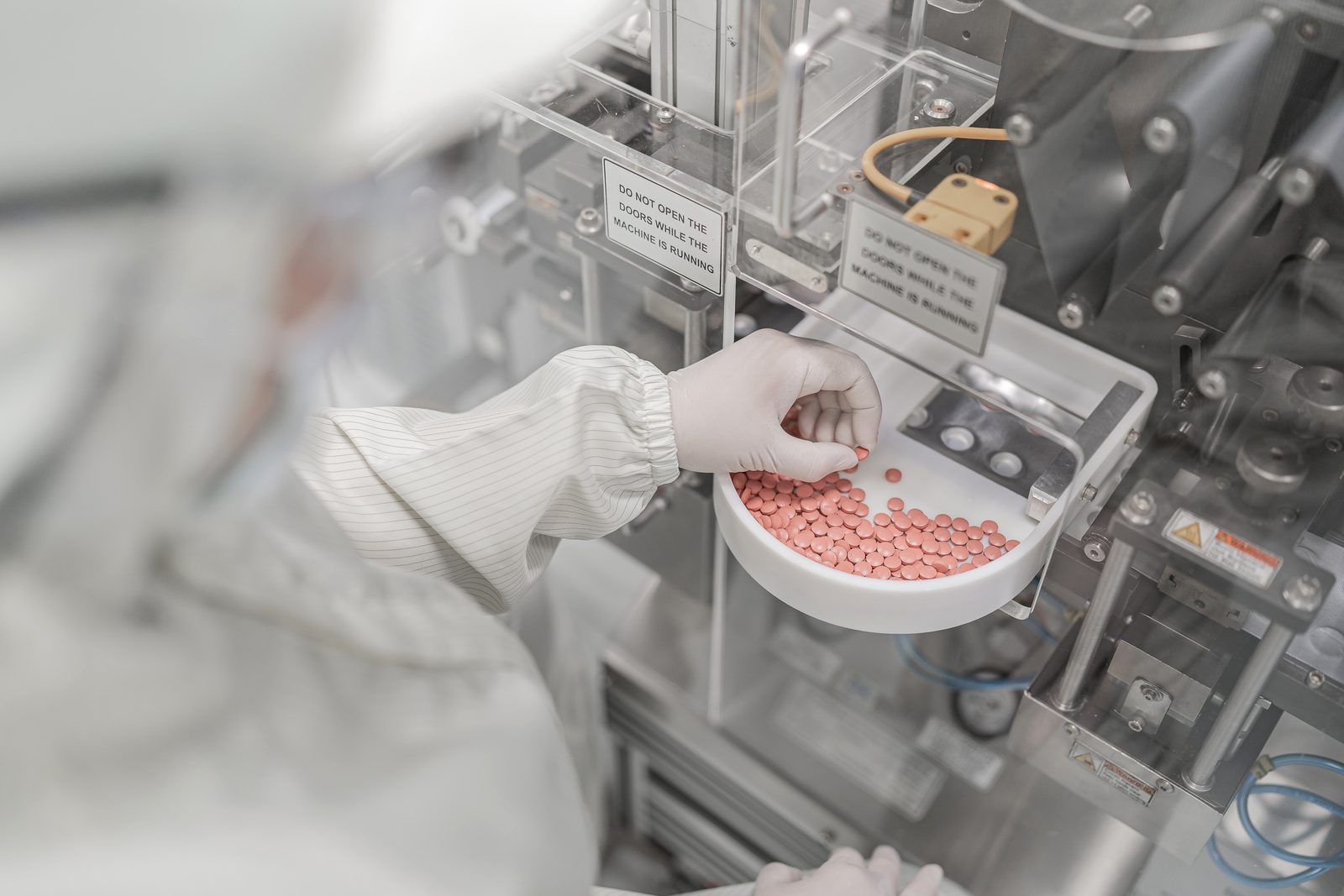 Technician inspecting pressed tablets in a cleanroom